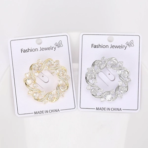 Close-up of gold and silver olive wreath brooches with cubic zirconia on jewelry cards