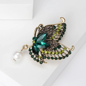 Detailed macro view of vintage butterfly brooch with green crystals and pearl drop