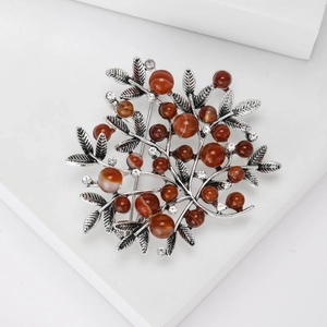 Detailed close-up of retro silver alloy berry brooch with red beads and rhinestones