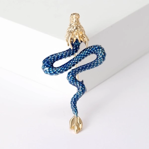 Detailed close-up of a blue enamel dragon brooch with golden metal accents and scales