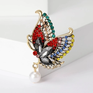 Detail of butterfly brooch with colorful rhinestones, grey gemstones and a white pearl