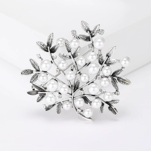 Detailed view of silver branch brooch with pearls and rhinestones on a white background