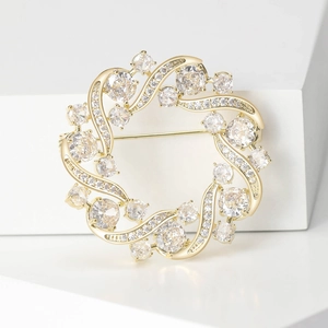 Detailed close-up of golden olive branch wreath brooch with sparkling cubic zirconia stones