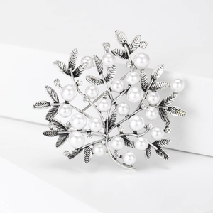 Macro shot of silver-colored alloy branch brooch with white pearls and sparkling rhinestones