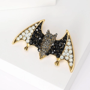 Gothic bat brooch in gold alloy with black and white rhinestones on geometric stand