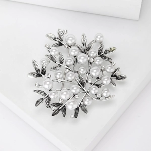 Detailed view of silver branch brooch featuring white pearls and sparkling rhinestones
