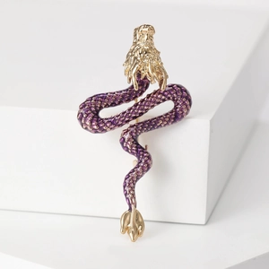 Detailed close-up of a purple enamel dragon brooch with textured gold accents
