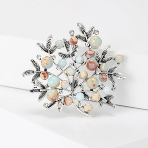 Macro view of vintage silver tree brooch featuring pearl berries and inlaid rhinestones