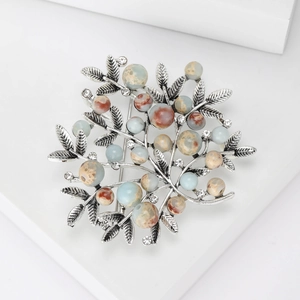 Detailed view of silver alloy branch brooch with colorful stone beads and rhinestones