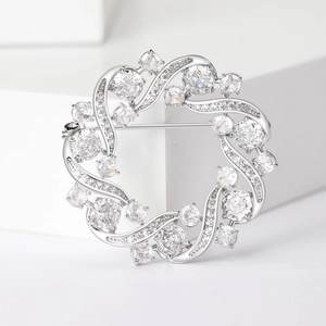 Elegant olive branch wreath brooch with cubic zirconia stones on white geometric props