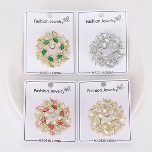 Ensemble de quatre broches couronnes en cristal de couleurs variées sur carte blanche