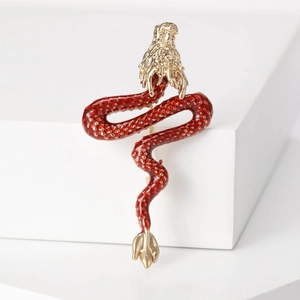Detailed view of enamel dragon brooch with red scales and gold finish on white blocks