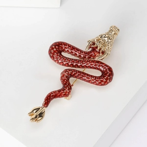 Detailed macro view of enamel dragon brooch with golden scales on a white display stand