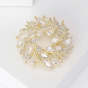 Vue macro d'une broche couronne dorée en zircon avec pierres marquises sur base blanche