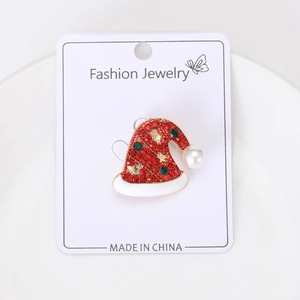 Detail of a gold Christmas hat brooch with red rhinestones on a fashion jewelry card