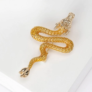 Detail of golden enamel dragon brooch featuring intricate scales and craftsmanship