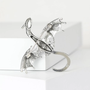 Back view of silver dragon brooch with security pin closure on a white stand