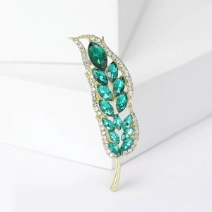Dettaglio della spilla a forma di spiga con cristalli marquise smeraldo e strass bianchi