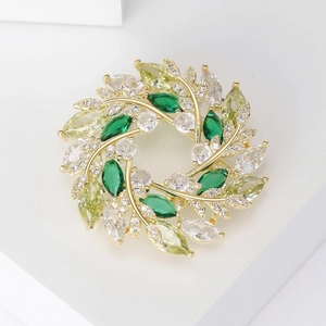 Détail de la broche couronne dorée avec feuilles en zircon vert et cristaux brillants