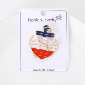 Dettaglio della spilla a forma di ancora nautica con smalto rosso, bianco e blu su carta