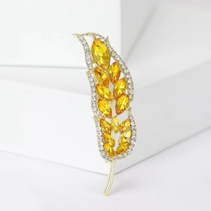 Dettaglio della spilla a spiga dorata con pietre marquise gialle e strass scintillanti