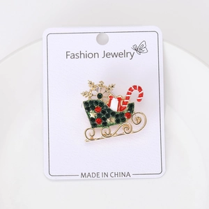 Detail of Christmas sleigh brooch with red and green rhinestones and golden snowflake
