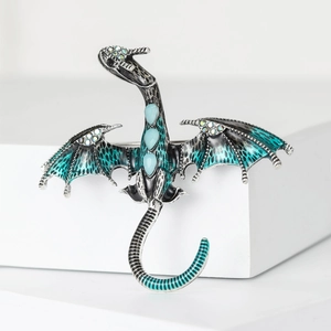Detail of silver dragon brooch with green enamel wings and blue gemstone inlay
