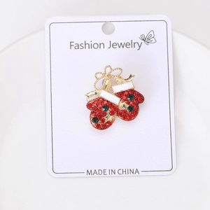 Detail of Christmas glove brooch with red rhinestones and golden bow on display card