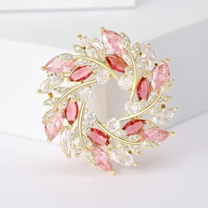 Vue détaillée d'une broche couronne dorée avec des pierres de zircon rose et rouge