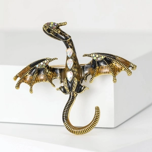 Macro shot of enamel dragon brooch with leopard wings and rainbow rhinestones