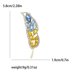Spilla a spiga di grano con cristalli blu e gialli e dimensioni su sfondo bianco puro
