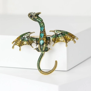 Detailed macro view of vintage gold dragon brooch with green enamel and sparkling crystals