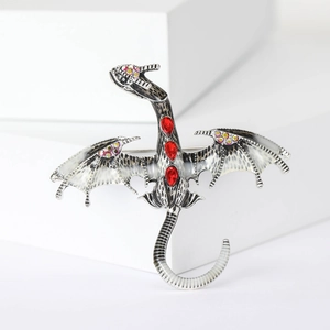 Detail of dragon brooch with red gemstones and enamel wings on a white geometric stand
