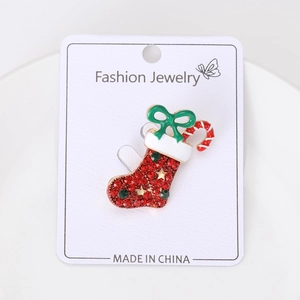 Détail d'une broche botte de Noël ornée de strass rouges et d'un nœud en émail vert