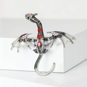 Macro detail of silver dragon brooch with red teardrop rhinestones and iridescent gems