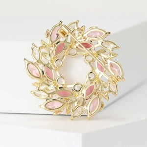 Broche couronne dorée élégante avec cristaux roses sur présentoir blanc moderne