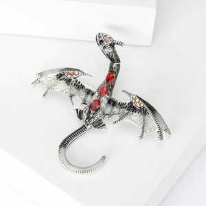 Detailed close-up of a dragon brooch with black enamel wings and red crystal accents