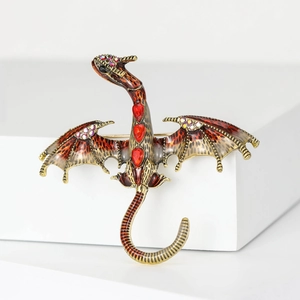Detail of vintage dragon brooch with bronze finish and red gemstones on white blocks