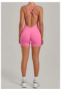 Detail view of pink yoga bodysuit with thin criss-cross back straps and athletic shorts