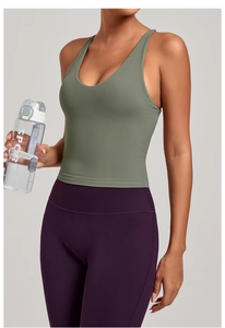 Gros plan sur le débardeur de yoga vert sauge à bretelles croisées et legging violet