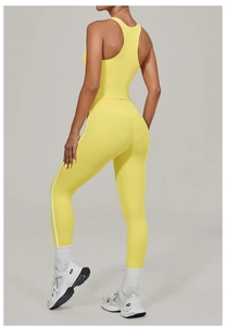 Detail view of yellow high-waisted yoga leggings with white side stripes and racerback top