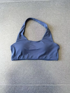 Vista piatta del reggiseno sportivo blu scuro con scollo all'americana e fascia elastica