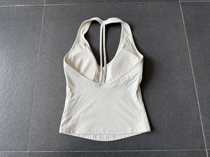 Haut de yoga dos nu beige posé à plat avec des lanières croisées en tissu élastique