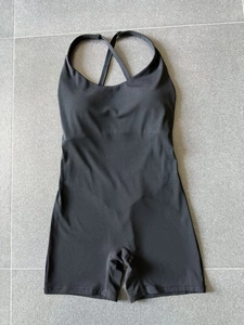 Detail view of black athletic romper featuring cross-back straps and high-stretch fabric