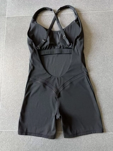 Flat lay of black yoga romper with crisscross back straps and adjustable buckles