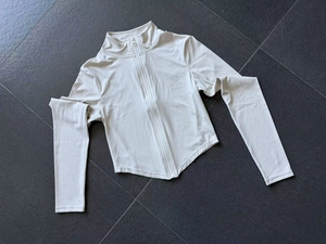 Détail d'une veste de yoga ajustée avec col montant et ourlet incurvé en beige