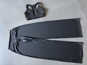 Platliggende weergave van een zwarte yoga tanktop en een wijde fitnessbroek met hoge taille