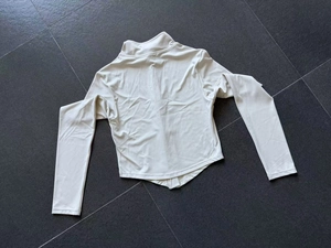Détail de l'ourlet arrondi et du tissu de sport beige lisse sur un haut de yoga