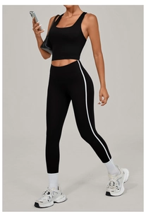 Detail of black high-waisted yoga leggings with white side stripes and cropped tank top