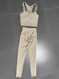 Flat lay of beige yoga set showing sports bra and high-waisted leggings with white stripes